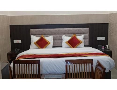 a bedroom with a large bed with two chairs at Hotel Park Blu, panipat in Pānīpat