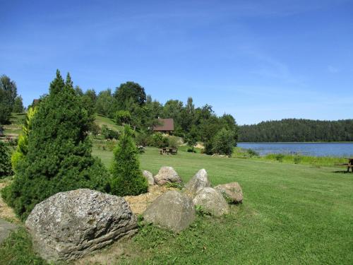 a group of rocks in a field next to a lake at Ezerkalni in Raiskums