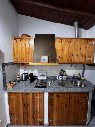a kitchen with a sink and wooden cabinets at É um Descanso in Campinho