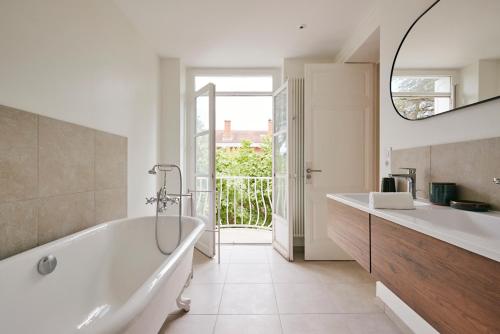 La salle de bains blanche est pourvue d'une baignoire et d'un lavabo. dans l'établissement Maison Martouret - Colodge, à Andrézieux-Bouthéon