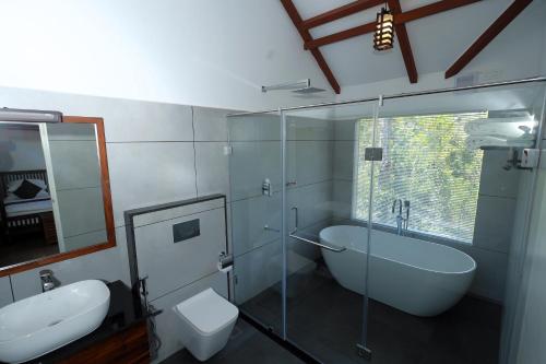 a bathroom with a glass shower and a toilet and a sink at Coffee and Pepper Plantation Homestay in Thekkady
