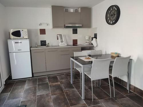 une cuisine avec une table, des chaises et un réfrigérateur dans l'établissement Mas Boucard II : plage cour et parking privés, à Frontignan