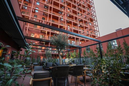 eine Außenterrasse mit Tischen und Stühlen und ein hohes Gebäude in der Unterkunft Garden Boutique Hotel in Tirana