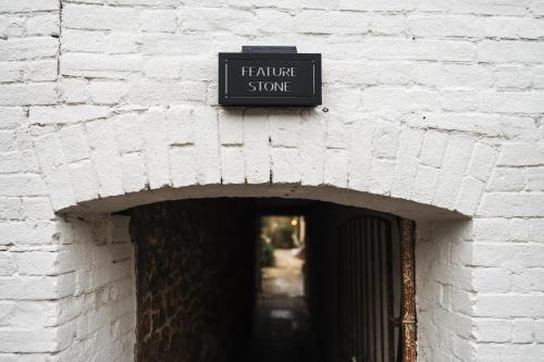 a sign for a hardware store on a brick wall at Feature Stone, Stunning Apartment, 2 x King Beds and Single, Sleeps 5 in Castle Cary