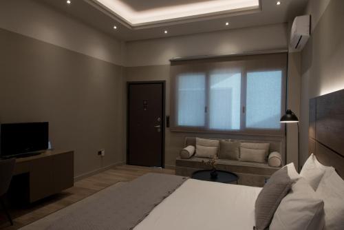 a bedroom with a bed and a couch and a television at ILION Air Host - near Athens International Airport in Markopoulo