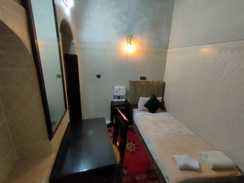 a small room with a bed and a mirror at RIAD Tamazouzt in Essaouira