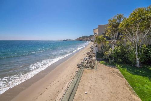 a view of a beach with a building and the ocean at SA Carbon Beach Suites in Malibu