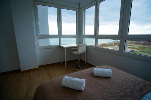 Schlafzimmer mit einem Bett, einem Schreibtisch und Fenstern in der Unterkunft Sunstay Seaview Guadalmar in Málaga