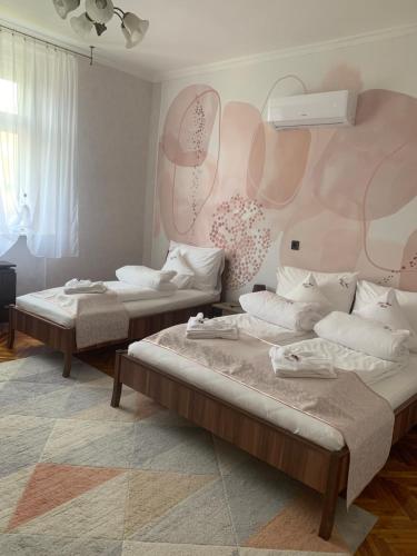 - 2 lits dans une chambre avec un mur rose dans l'établissement Szent István Apartman, à Makó