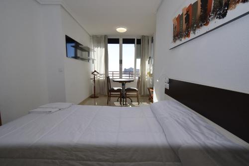 a bedroom with a large bed and a table at Pintor Rosales 3 dormitorios mirando al mar - Fincas Arena in Benidorm