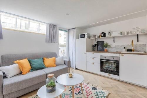 ein Wohnzimmer mit einem Sofa und einem Tisch in der Unterkunft Appartement proche Arc Triomphe 4P in Paris