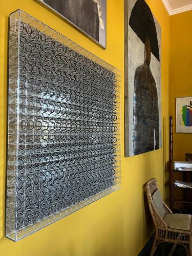 a wall with a metal art on a yellow wall at artemare in Viareggio