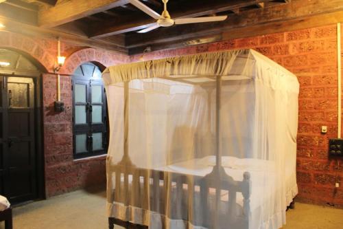 ein Himmelbett in einem Zimmer mit Ziegelwand in der Unterkunft Konkan Nest Resort in Ganpatipule