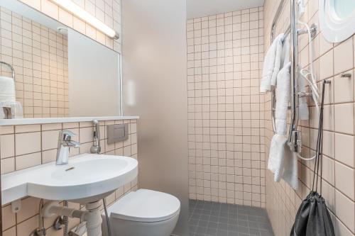 ein Badezimmer mit einem Waschbecken, einem WC und einem Spiegel in der Unterkunft Hotel Red & Green in Närpiö