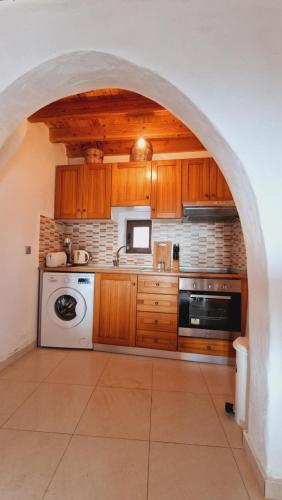 an archway in a kitchen with a washer and dryer at Yiannis Village house in Asklipiḯon