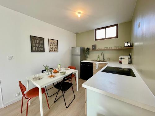 une cuisine avec un comptoir blanc et une table blanche dans l'établissement Le Rêve Ebroïcien, T3 Sur équipé - Gare - centre, à Évreux