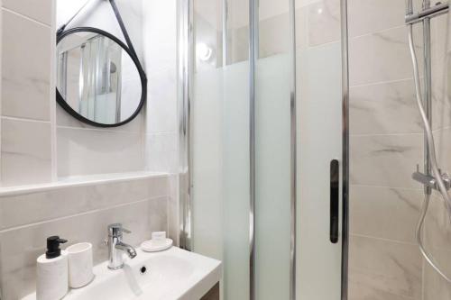 een badkamer met een douche, een wastafel en een spiegel bij Splendide appartement proche Opéra Garnier - 6P in Parijs