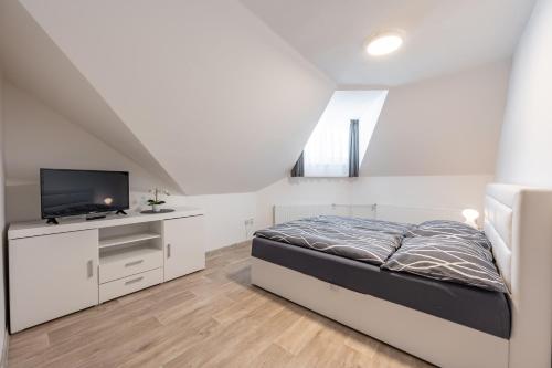 a white bedroom with a bed and a tv at Vila Astoria in Luhačovice