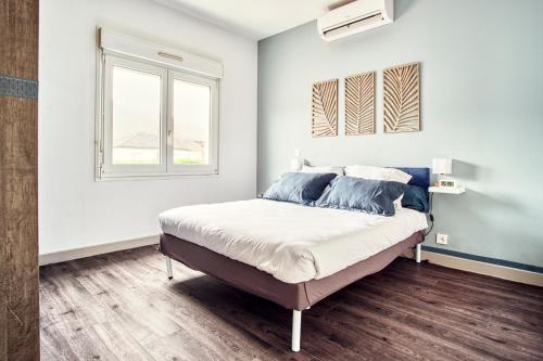 - une chambre blanche avec un lit et des oreillers bleus dans l'établissement Bel appartement tout confort en Aveyron, à Firmi