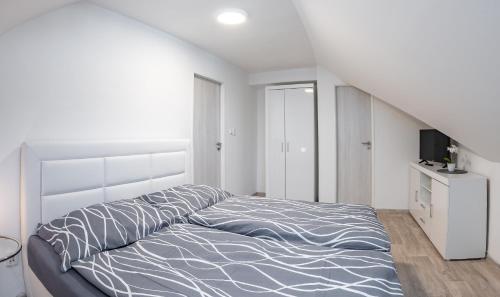 a white bedroom with a bed and a staircase at Vila Astoria in Luhačovice