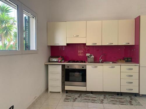 una cucina con armadi bianchi e parete viola di CASA VACANZA GALLIPOLI a Matino
