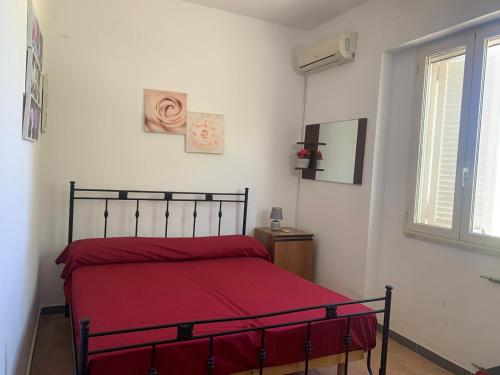una camera da letto con un letto con lenzuola rosse e una finestra di CASA VACANZA GALLIPOLI a Matino