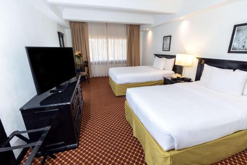 a hotel room with two beds and a flat screen tv at Clarion Hotel Real Tegucigalpa in Tegucigalpa