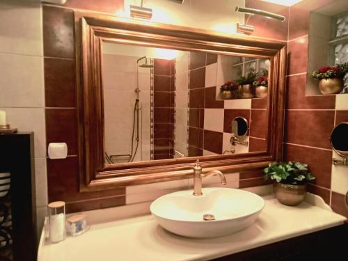 La salle de bains est pourvue d'un lavabo et d'un grand miroir. dans l'établissement Classic Apartment With Beautiful View, à Kastoria