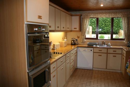 uma cozinha com armários brancos e um forno com placa de fogão em Emerald Bank Cottage em Uldale