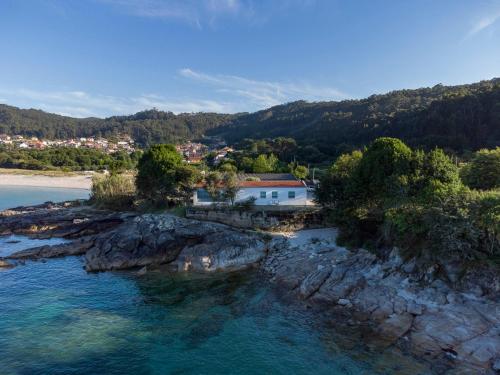 eine Luftansicht eines Hauses auf einer felsigen Insel im Wasser in der Unterkunft A Factoria Beach House by Prishomes in Hio