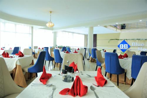 un salón de banquetes con mesas blancas y sillas azules en Blue Birds International Hotel en Addis Abeba