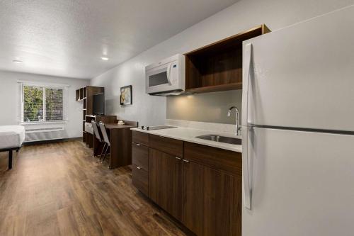 a kitchen with a white refrigerator and wooden cabinets at WoodSpring Suites Yorktown Newport News in Newport News