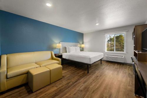 WoodSpring Suites Yorktown Newport News في نيوبورت نيوز: غرفه فندقيه بسرير واريكه