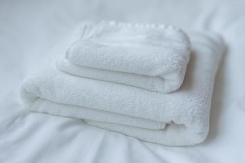three white towels stacked on top of a bed at SKY GATEスカイツリー徒歩3分の貸切ヴィラ/成田羽田直通/浅草徒歩15分 in Tokyo