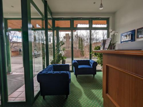 a room with two blue chairs and glass doors at Acron-Hotel Quedlinburg in Quedlinburg