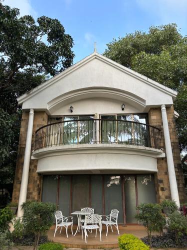 Casa con balcón con mesa y sillas en Silverador Resort, en Thane