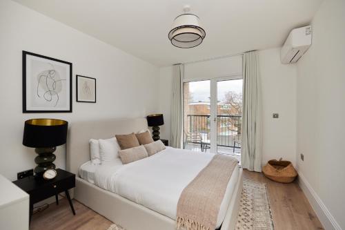 a white bedroom with a bed and a window at The Wembley Park Sanctuary - Stunning 2BDR Flat with Balcony in London