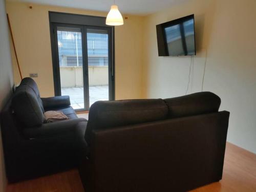 sala de estar con sofá y TV de pantalla plana en Disfruta del pirineo oscense, en Sabiñánigo