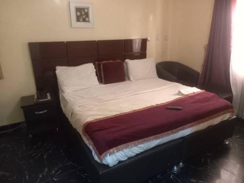 Schlafzimmer mit einem großen Bett mit einem Kopfteil aus Holz in der Unterkunft The Resident Hotel in Owerri