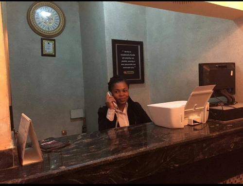 una mujer sentada en un mostrador hablando por celular en The Resident Hotel, en Owerri