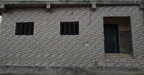 ein Backsteingebäude mit zwei Fenstern und einer Tür in der Unterkunft Family house 2 bedrooms, 2 sdb, near Center of Nador & Airport in Selouane