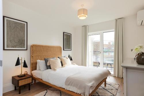 een witte slaapkamer met een groot bed met witte lakens bij The Wembley Park Wonder - Charming 2BDR Flat with Balcony in Londen