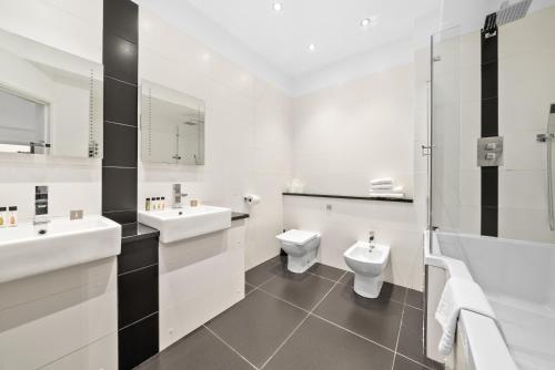 a white bathroom with two sinks and a toilet at Apartment 2, 48 Bishopsgate by City Living London in London