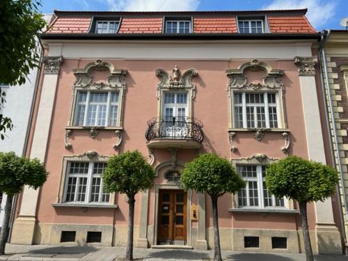 een roze gebouw met bomen ervoor bij Nest in Győr