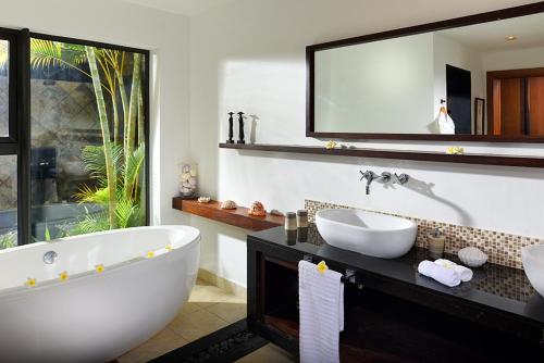 La salle de bains est pourvue d'une baignoire, d'un lavabo et d'un miroir. dans l'établissement Villa Kaz' Grenadine, à Bel Ombre