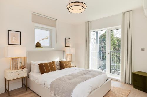 een witte slaapkamer met een bed en een raam bij The Wembley Park Retreat - Modern 2BDR Flat with Balcony in Londen