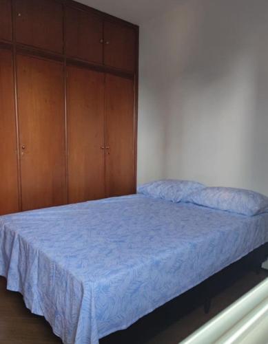 a bedroom with a bed with blue sheets and wooden cabinets at Apartamento no Centro de Campo Grande in Campo Grande