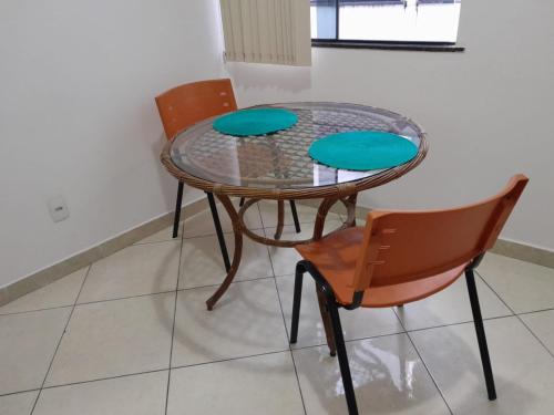 a glass table with two chairs and a table with blue cushions at Apartamento completo e bem localizado 302 in Vitória da Conquista