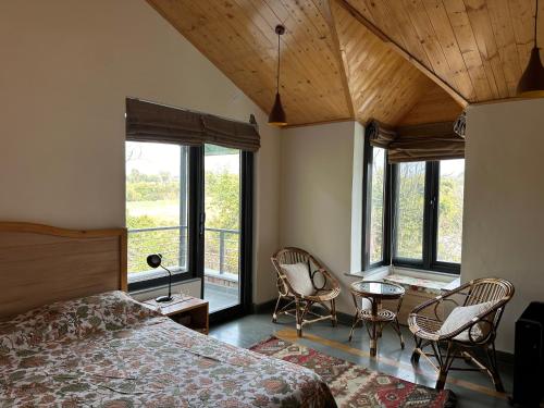 een slaapkamer met een bed, stoelen en ramen bij Terra Cottage in Palāhu