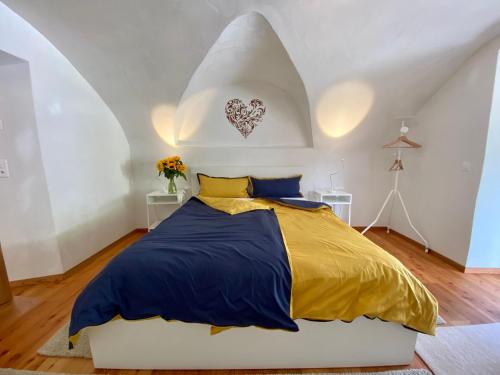 Schlafzimmer mit einem Bett mit gelber und blauer Decke in der Unterkunft Engadin Holidays ch - Chasa 32 in Guarda in Guarda